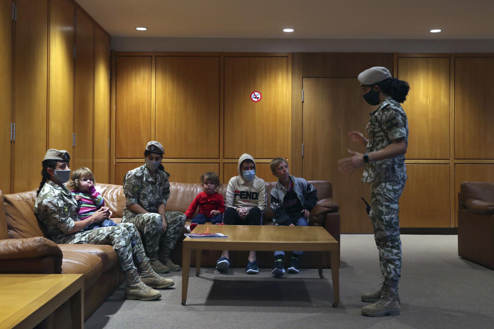 Members of the Lebanese General Security forces sit with Albanian children during an operation to take them back home to Albania from al-Hol, northern Syria, at the Rafik Hariri International Airport in Beirut, Lebanon, Tuesday, Oct. 27, 2020. The repatriation of four children and a woman related to Albanian nationals who joined Islamic extremist groups in Syria "is a great step" to be followed by more repatriations, Albania's prime minister said Tuesday. (AP Photo/Bilal Hussein)