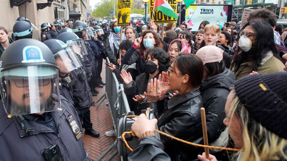 New York City police officers in riot gear stand guard as demonstrators chant slogans outside the Columbia University campus on Thursday in New York. - Mary Altaffer/AP