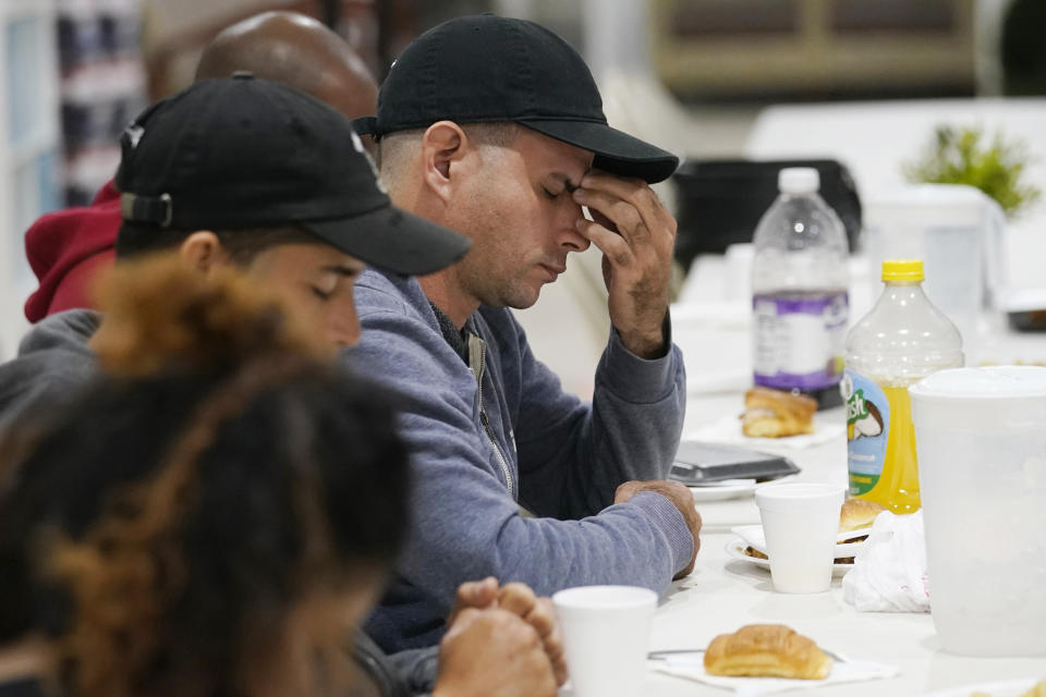 Roberto Sotolongo prays after dinner at the Iglesia Rescate, Tuesday, Feb. 21, 2023, in Hialeah, Fla. Sotolongo, from Havana, Cuba, crossed the U.S. Mexican border into the U.S. in November, leaving behind his wife and children. Sotolongo, a carpenter by trade, finds himself in limbo without a work permit to sustain himself and help his family in Cuba. (AP Photo/Marta Lavandier)