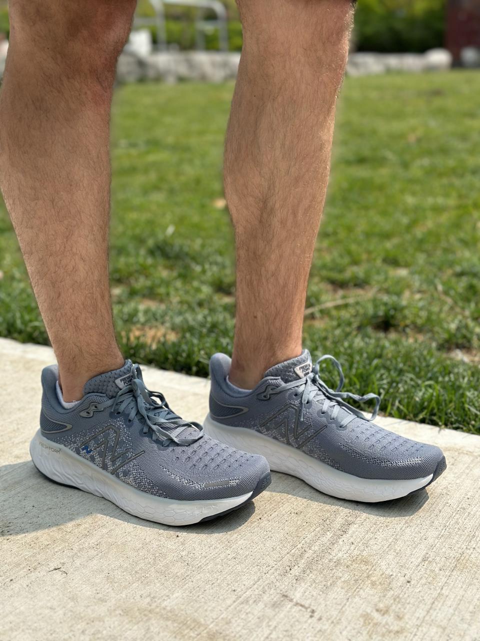 man wearing grey running shoes New Balance 1080 V12 on sidewalk near grass, running shoes review