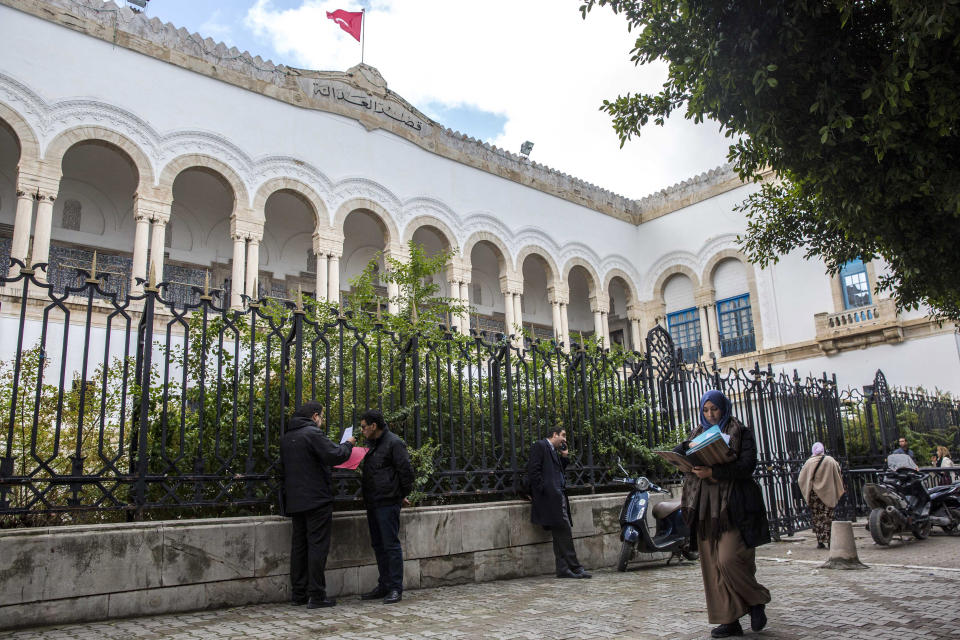 People walk in front of the Tunis Palace of Justice in Tunis, Tuesday, Jan.29, 2019. More than 40 people have been summoned to face trial over Tunisia's deadliest attack in a Mediterranean resort in 2015. The trial reopened on Tuesday in Tunis, more than 3-1/2 years after the attack on the Imperial Hotel in the beach resort of Sousse left 38 people dead, mostly British tourists.(AP Photo/Hassene Dridi)