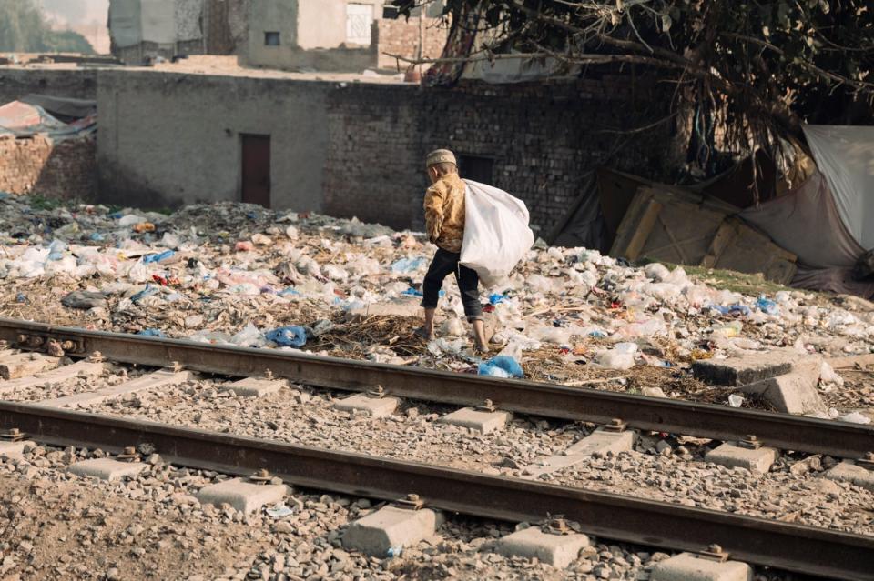 A young boy searches the rubbish for aluminium cans or plastic bottles to sell (Paddy Dowling)