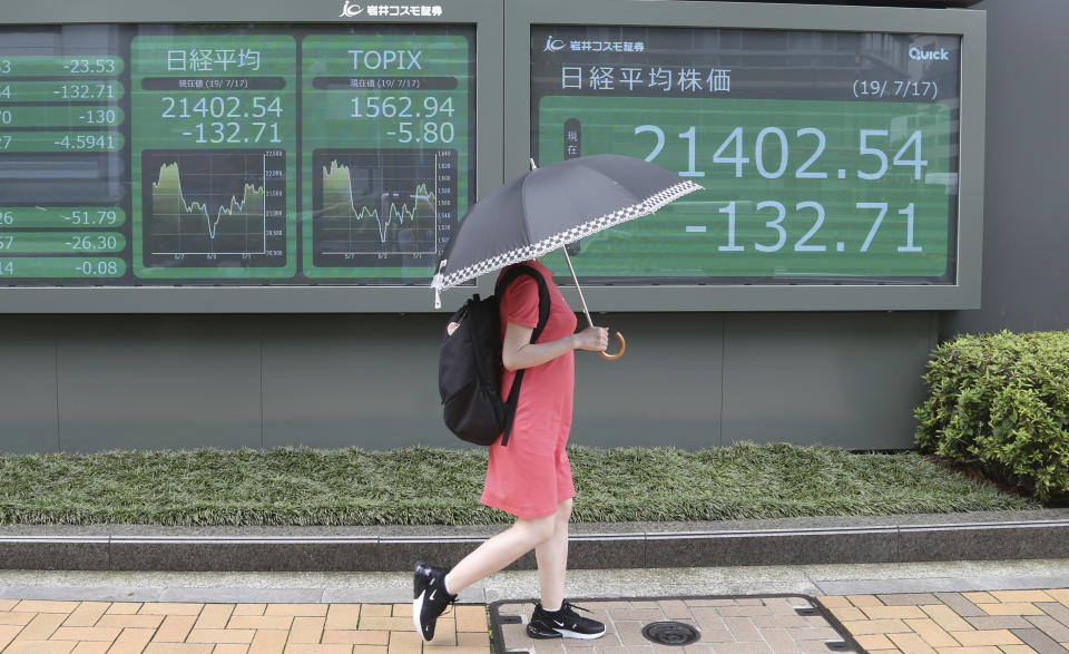 A woman walks by an electronic stock board of a securities firm in Tokyo, Wednesday, July 17, 2019. Asian stocks were mixed Wednesday as Wall Street ended a five-day winning streak after the first big round of corporate earnings reports. (AP Photo/Koji Sasahara)