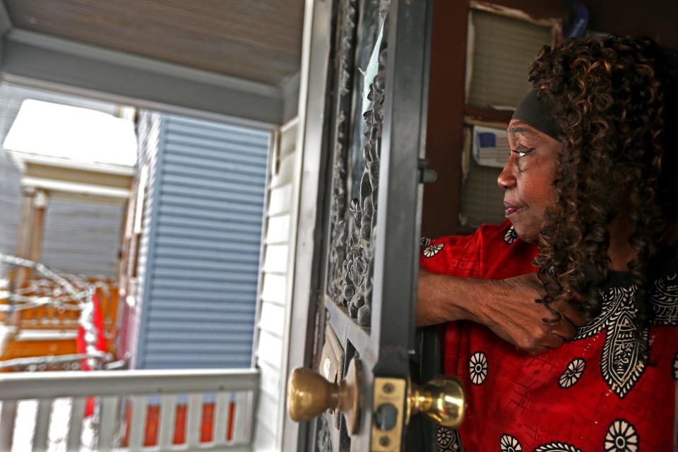 Alice Cartwright looks toward the house where six people were found dead Sunday. Cartwright, who has lived at the home since 1993, said Monday that hearing gunshot sounds isn’t unusual in her neighborhood.