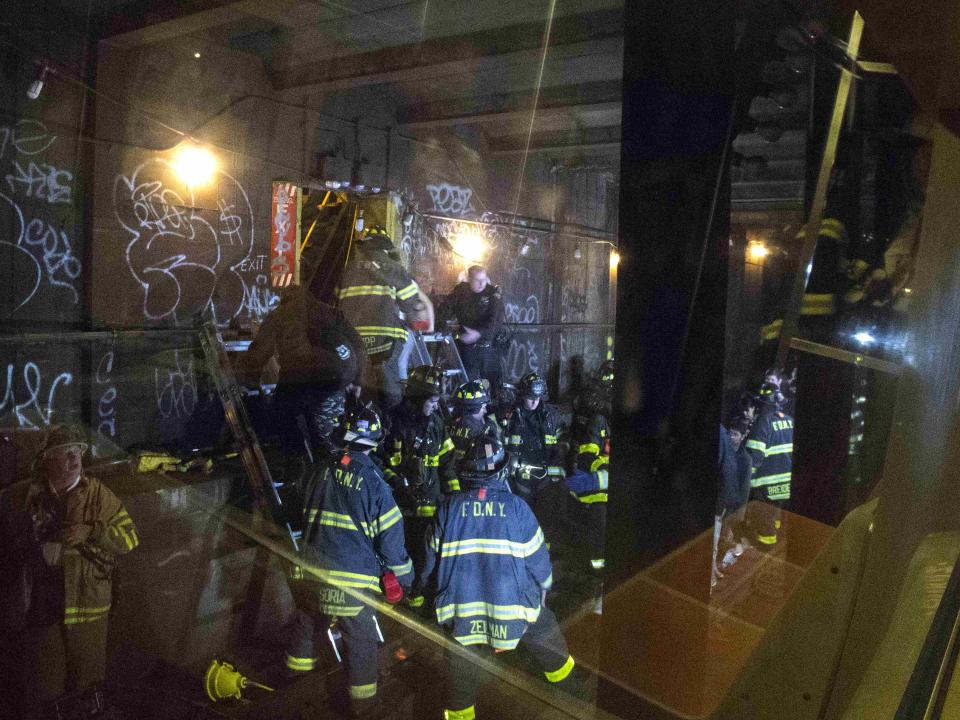 Firefighters and rescue officials are seen through the window of the derailed "F" train as they help passengers escape through a subway tunnel emergency exit in the Woodside neighborhood located in the Queens borough of New York May 2, 2014. (REUTERS/Connie Wang)