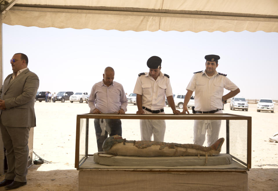 Egyptian tourist police stand with a recently discovered artifact at the Memphis necropolis during an event opening the Bent Pyramid and its satellites for visitors in Dashur, Egypt, Saturday, July 13, 2019. An Egyptian mission led by Dr. Mostafa Waziri discovered a collection of stone, clay and wooden sarcophagi which some of it still houses its mummies in addition to wooden funerary masks and instruments used in cutting stones from the Late period. (AP Photo/Maya Alleruzzo)