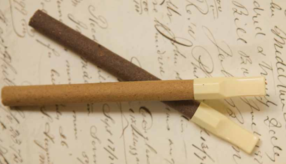 Two old-style cigarettes with filters on top of a piece of paper with old-style handwriting.
