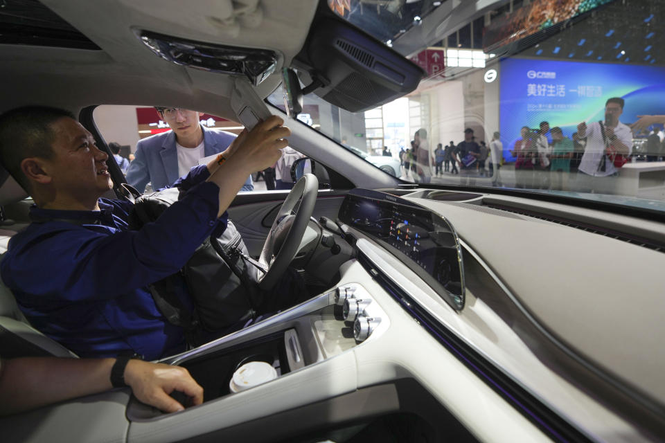 A visitor checks an Exeed C-DM car during the China Auto Show in Beijing, China, Friday, April 26, 2024. China's vision of the future of the automobile electrified and digitally connected is on display at the ongoing Beijing auto show. (AP Photo/Tatan Syuflana)