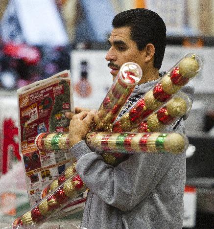 FILE-In this Friday, Nov. 25, 2011, file photo, Sergio Lira, of Phoenix, holds Christmas bulbs as he shops at the Home Depot in Phoenix. Americans are expected to spend more during what's traditionally the busiest shopping season of 2012, but they're not exactly ready to shop 'til they drop like they have been in the past two years. The National Retail Federation, the nation's largest retail trade group, said Tuesday, Oct. 2, 2012, that it expects sales during the winter holiday shopping period in November and December to rise 4.1 percent this year. (AP Photo/Arizona Republic, Tom Tingle) MARICOPA COUNTY, NO SALES