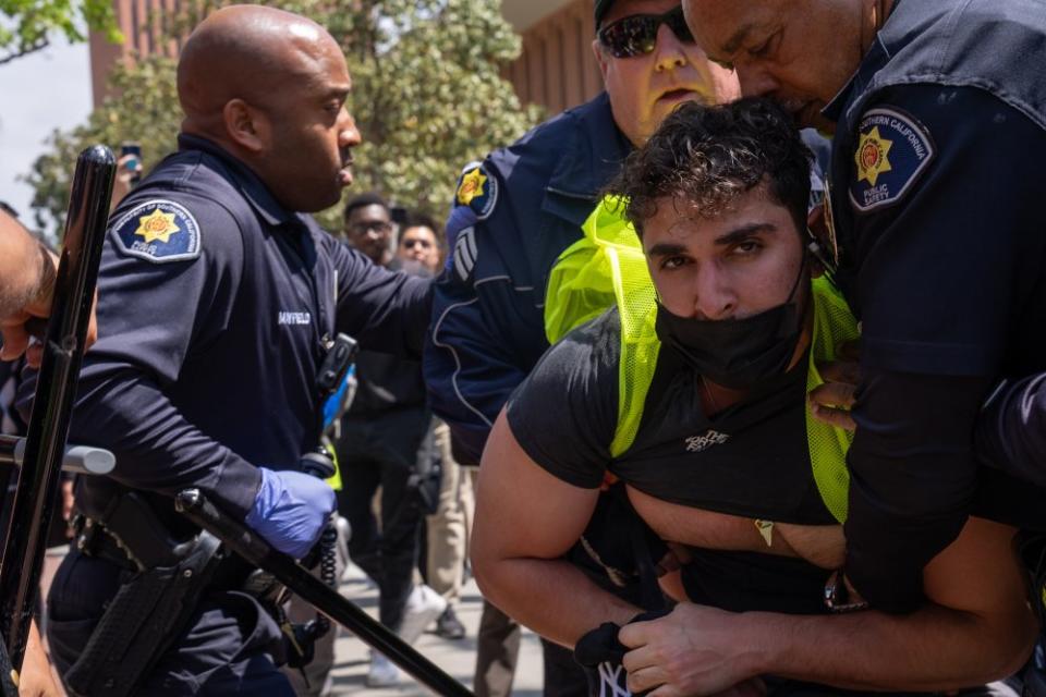 USC Department of Public Safety officers detain a protester on April 24, just hours after the "Gaza Solidarity Occupation" had first been set up in Alumni Park. DPS would later release the protester to chants of “The people united will never be defeated.”<span class="copyright">Henry Kofman for Daily Trojan</span>