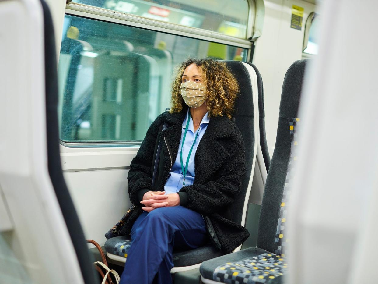 Nurse wearing mask and scrubs while sitting on a train