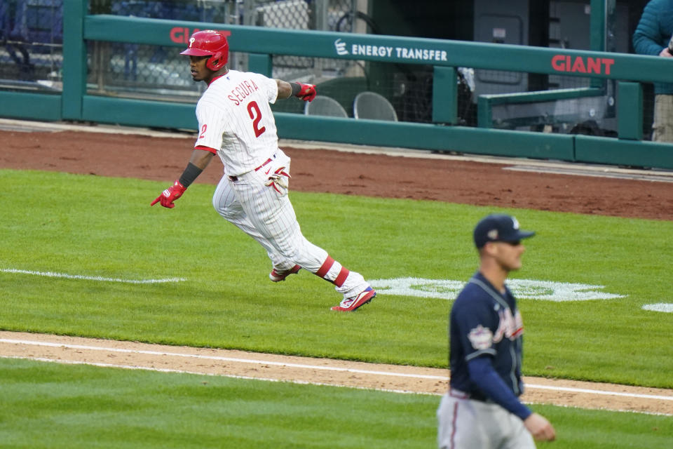 Philadelphia Phillies' Jean Segura, left, reacts after hitting a game-winning RBI-single off Atlanta Braves relief pitcher Nate Jones during the 10th inning of an opening day baseball game, Thursday, April 1, 2021, in Philadelphia. (AP Photo/Matt Slocum)