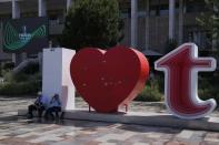 Two men sit in front of Opera building ahead of the Europa Conference League final between Roma and Feyenoord in Tirana, Albania, Wednesday, May 25, 2022. (AP Photo/Thanassis Stavrakis)