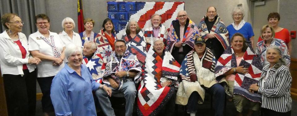 Veterans and their quilters from Blue Ridge Quilts of Valor pose following a June 3 ceremony at the Henderson County Library. From left to right are, front row: Peggy Natoli, Dana Hayman, Fred Hankinson, Bill Savage, Jack Simmons, Kristal Brown, Mary Parker; back row: Evelyn Uhrlass, Bonnie Cunningham, Elaine McDonald, Didi Salvatierra, Stacie Litsenberger, Meghan LaRose, Robert Cahill, Mike Butrum, Alan Ehrlich, Joanne Shafer, Linda Bomberger, Sheila Solen.