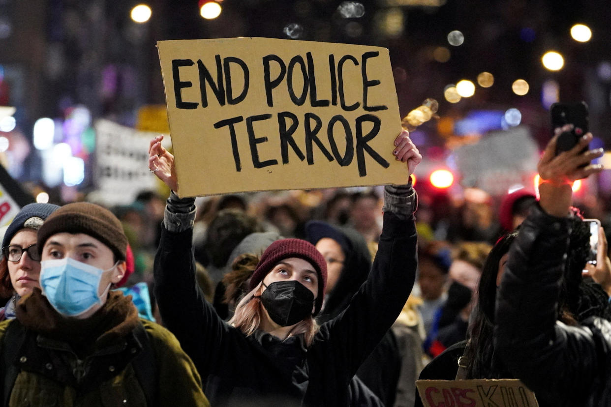 A person in a crowd of protesters in New York City holds a sign that reads: End police terror.