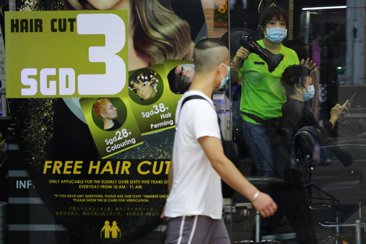 SINGAPORE - APRIL 05:  A hairdresser wearing protective mask attends to a customer on April 5, 2020 in Singapore. The Singapore government will be closing non-essential workplaces and schools temporarily for a month from April 7 to contain the spread of the COVID-19 infection. The Ministry of Health reported 120 new cases on April 5, the largest daily increase since the outbreak in January, bringing the country's total to 1309.  (Photo by Suhaimi Abdullah/Getty Images)