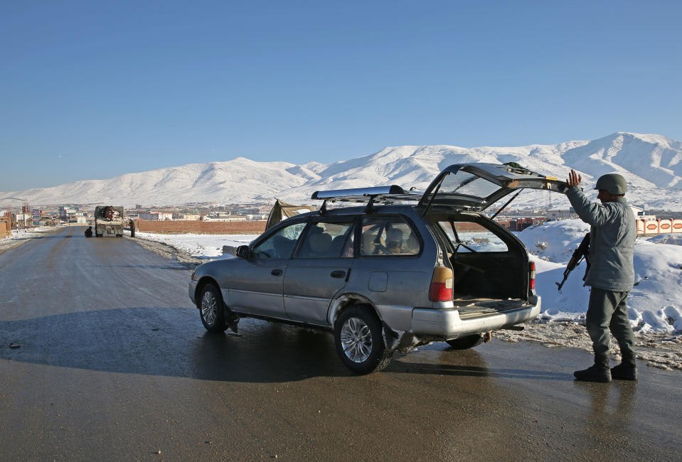 In this Thursday, Jan. 9, 2014 photo, Hekmatullah, an Afghan policeman searches the trunk of a car at a check post in Kabul-Bamiyan road, on the outskirts of Maidan Shahr, capital of Wardak province Afghanistan. Locals call it "Death Road." The 30 kilometer (18 mile) stretch of road heading west from here has seen so many beheadings, kidnappings and other Taliban attacks in recent years that it's become a virtual no man's land, cutting off the Hazara minority from their homeland in Afghanistan's rugged mountainous center. (AP Photo/Massoud Hossaini)
