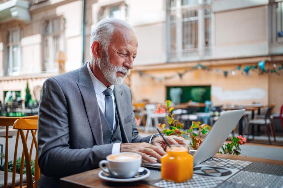 Businessperson typing on laptop outside restaurant.