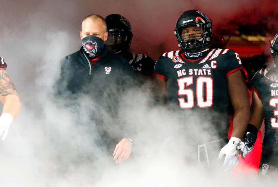 N.C. State’s Grant Gibson (50) and head coach Dave Doeren lead the team onto the field before N.C. State’s game against Miami at Carter-Finley Stadium in Raleigh, N.C., Friday, Nov. 6, 2020.