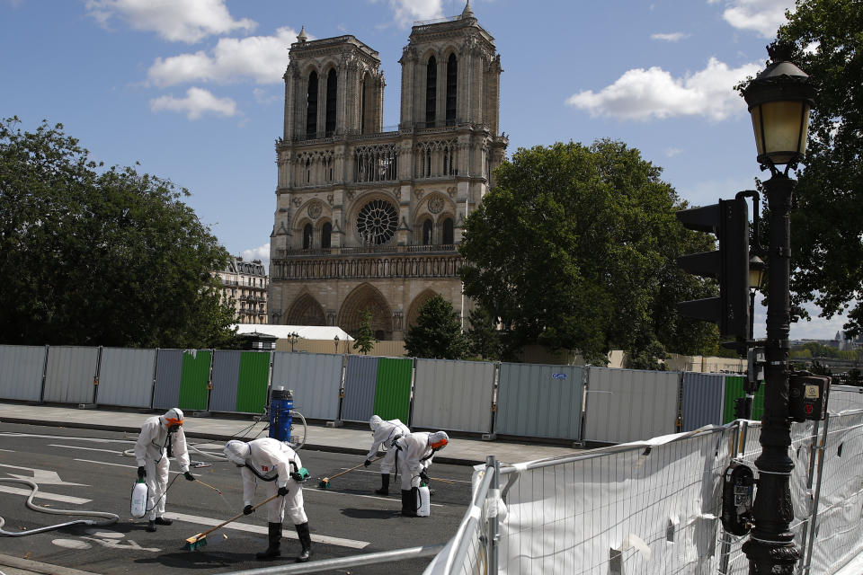 Workers clean the area in front of Notre Dame cathedral, Monday, Aug. 19, 2019 in Paris. Specialists shoring up fire-damaged Notre Dame Cathedral were returning to the Paris site on Monday for the first time in nearly a month, this time wearing disposable underwear and other protective gear after a delay prompted by fears of lead contamination. (AP Photo/Francois Mori)