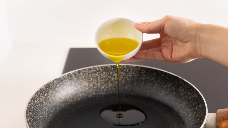 pouring olive oil into pan