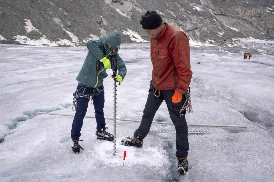 Team members of Swiss Federal Institute of Technology glaciologist and head of the Swiss measurement network 'Glamos', Matthias Huss, drill holes into the Rhone Glacier near Goms, Switzerland, Friday, June 16, 2023. Now dwindling at an alarming rate because of human-caused climate change, the group monitors what is left of the country's glaciers in an attempt to slow their demise. (AP Photo/Matthias Schrader)