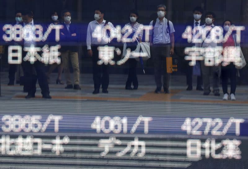 Passers-by wearing protective face masks are reflected on a screen of blank prices in a stock quotation board after Tokyo Stock Exchange temporarily suspended all trading due to system problems