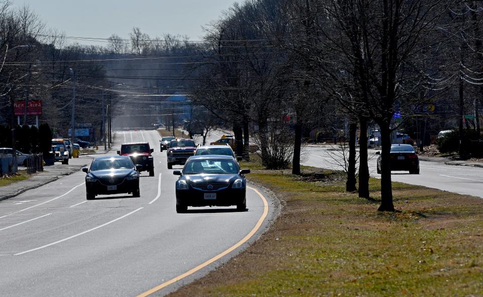 On Mill Street, cars pass vehicles parked in the on-street parking spots.