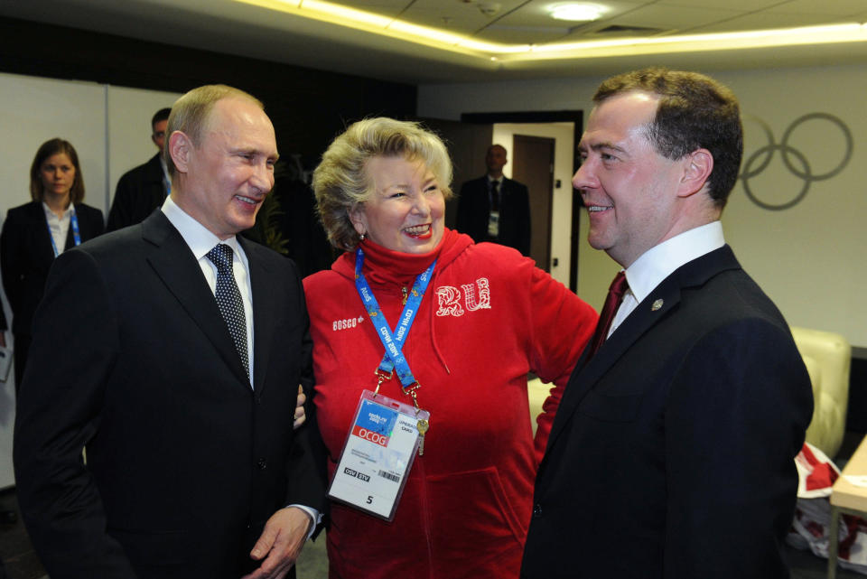 FILE- Russian President Vladimir Putin, left, and Prime Minister Dmitry Medvedev, right, listen to figure skating coach Tatiana Tarasova in the presidential lounge before the 2014 Winter Olympics closing ceremony, in Sochi, Russia, Sunday, Feb. 23, 2014. The 2022 Beijing Games' first major scandal has managed to involve 15-year-old figure skater Kamila Valieva who has tested positive for using a banned heart medication that may cost her Russia-but-not-really-Russia team a gold medal in team competition."This is some kind of a fake," said Tarasova. "She's only 15, what do you mean doping?" (RIA Novosti Kremlin, Mikhail Klimentyev, Presidential Press Service/Pool Photo via AP)