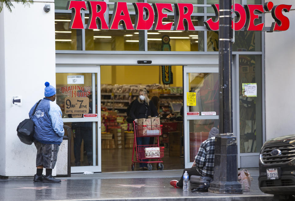 A person waits to enter a Trader Joe's grocery store, as a shopper leaves in the Hollywood section of Los Angeles on Tuesday, March 24, 2020. (AP Photo/Damian Dovarganes)