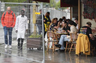 Patrons sit outside a restaurant behind some remaining security barriers on a street along the River Seine, now opened to foot traffic after Friday's opening ceremony at the 2024 Summer Olympics, Saturday, July 27, 2024, in Paris, France. (AP Photo/Rebecca Blackwell)