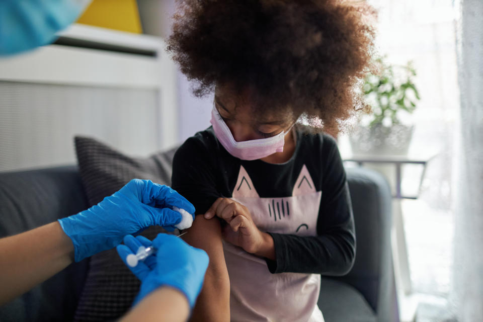 A child wearing a face mask receives a vaccine.