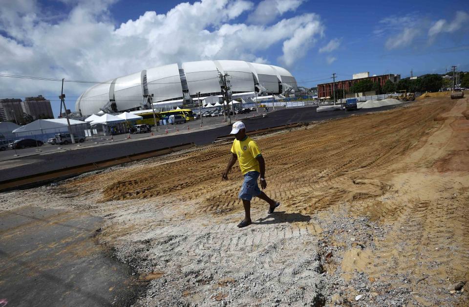 A worker, wearing a Brazilian football jersey, strolls through a construction site next to the Dunas arena soccer stadium in Natal, June 12 , 2014. Mexico will face Cameroon in their 2014 World Cup football match here on June 13. REUTERS/Dylan Martinez