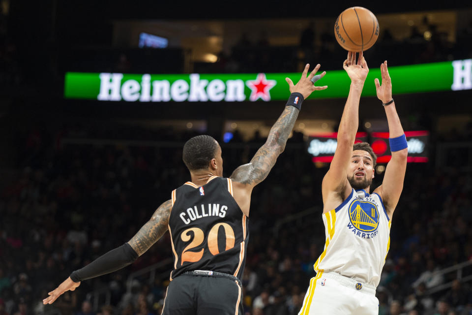 Golden State Warriors guard Klay Thompson, right, shoots a 3-point basket against Atlanta Hawks forward John Collins during the first half of an NBA basketball game, Friday, March 17, 2023, in Atlanta. (AP Photo/Hakim Wright Sr.)