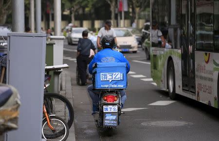 A courier of Ele.me food delivery smartphone application travels on his electric bicycle along a street in Shanghai, China, October 9, 2015. REUTERS Aly Song