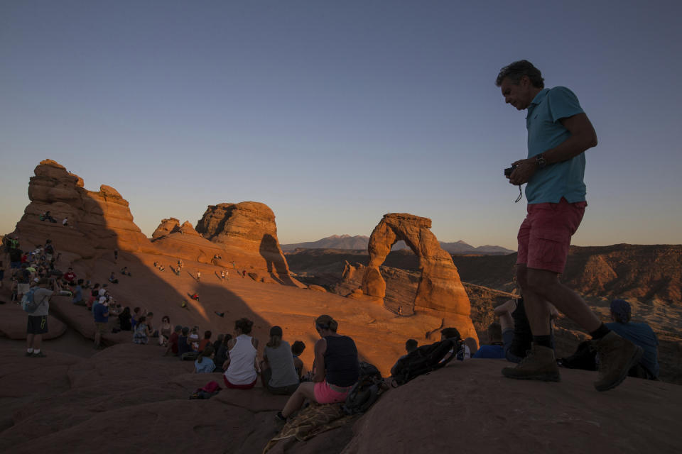 FILE - People gather to watch the sunset at Delicate Arch in Arches National Park near Moab, Utah, Sept. 8, 2016. Arizona's Grand Canyon National Park and all five national parks in Utah will remain open if the U.S. government shuts down, Sunday, Oct. 1, 2023. Arizona Gov. Katie Hobbs and Utah Gov. Spencer Cox say that the parks are important destinations and local communities depend on dollars from visitors. (Spenser Heaps/The Deseret News via AP, File)