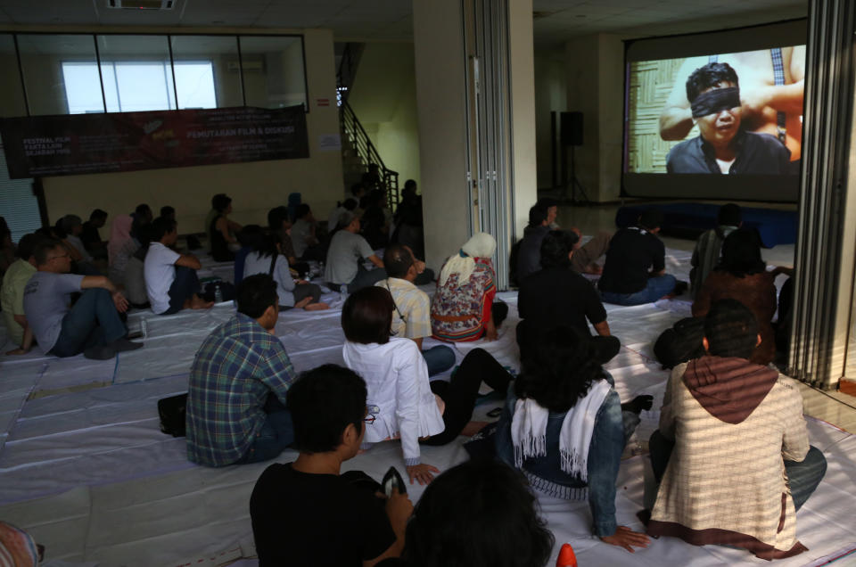 In this Monday, Sept. 30, 2013 photo, people watch documentary film "The Act of Killing" in Jakarta, Indonesia. The new American-directed documentary challenges widely held views about hundreds of thousands of deaths carried out across Indonesia from 1965 to 1966 in the name of fighting communism. It explores the country’s darkest open secret by allowing former mass killers to re-enact their horrors on screen. (AP Photo/Tatan Syuflana)