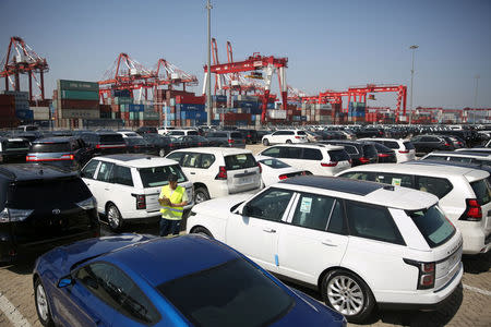 A worker inspects imported cars at a port in Qingdao, Shandong province, China May 23, 2018. REUTERS/Stringer