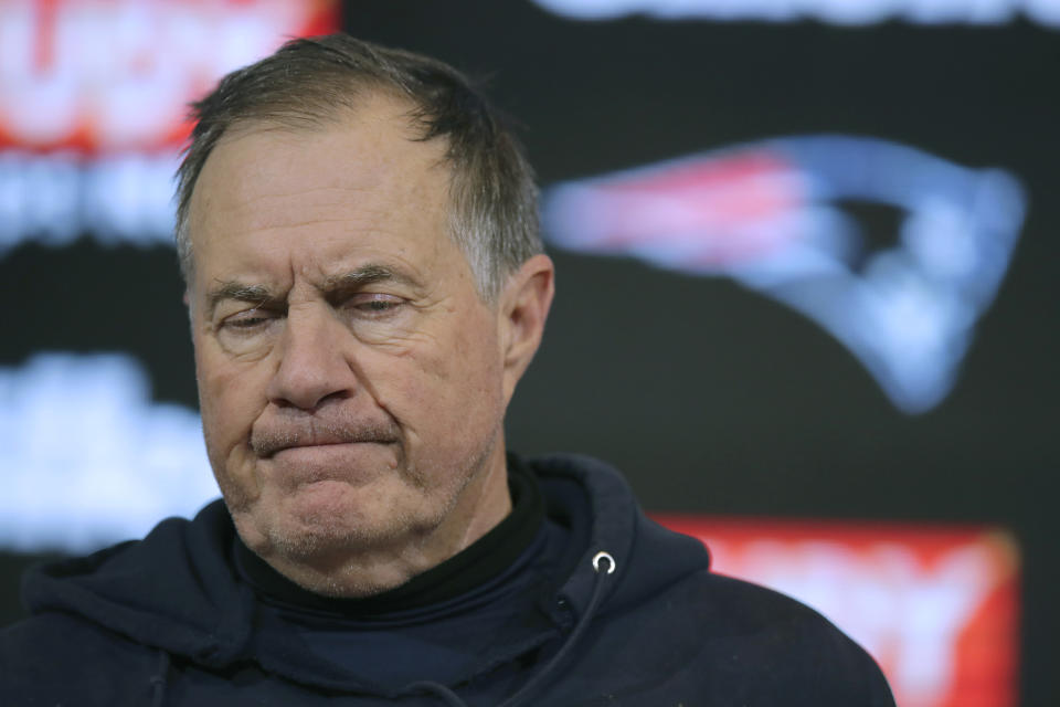 Bill Belichick frowns while standing at a podium.