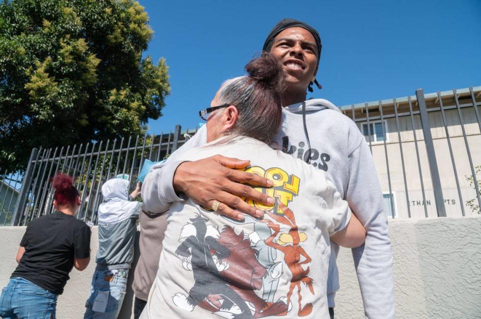 Gada Aguilar, front, hugs Tae Ziegler, 17, in front of the Ethan Apartments in Arden Arcade on Tuesday. Aguilar said she and the other people constructing the memorial were unsure where exactly along the sidewalk the 15-year-old victim was shot.