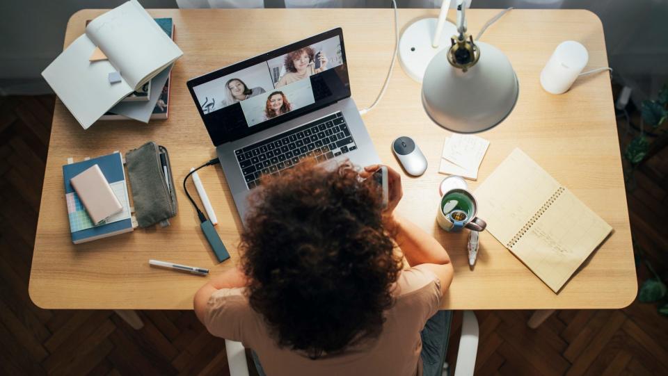 Flattening the curve: a happy woman sitting at home and talking to her friends or colleagues in a meeting using her laptop computer.