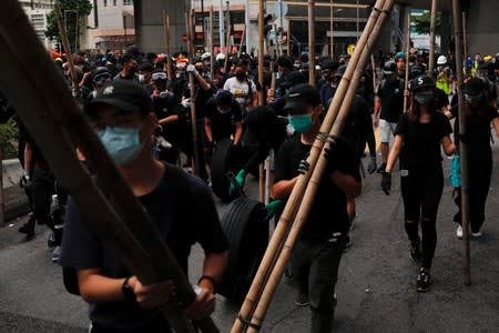 Anti-government protesters hold bamboo poles during a demonstration following a government's ban on face masks under emergency law, at Sham Shui Po, in Hong Kong