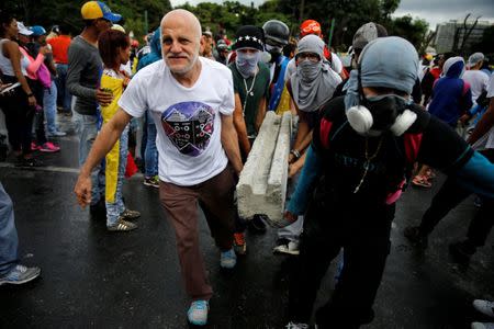 Demonstrators carry a piece of concrete as they gather in front of an Air Force base during a rally against Venezuelan President Nicolas Maduro's government in Caracas, Venezuela, June 24, 2017. REUTERS/Ivan Alvarado