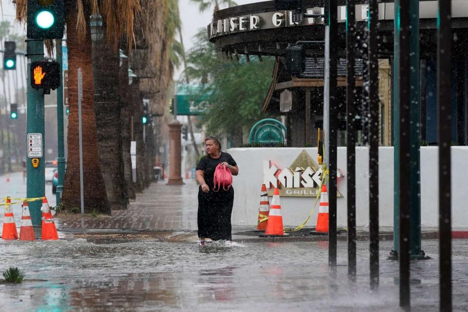 PHOTO: A woman walks through standing water as Tropical Storm Hilary approaches Palm Springs, California, U.S., August 20, 2023. (Bryan Woolston/Reuters)