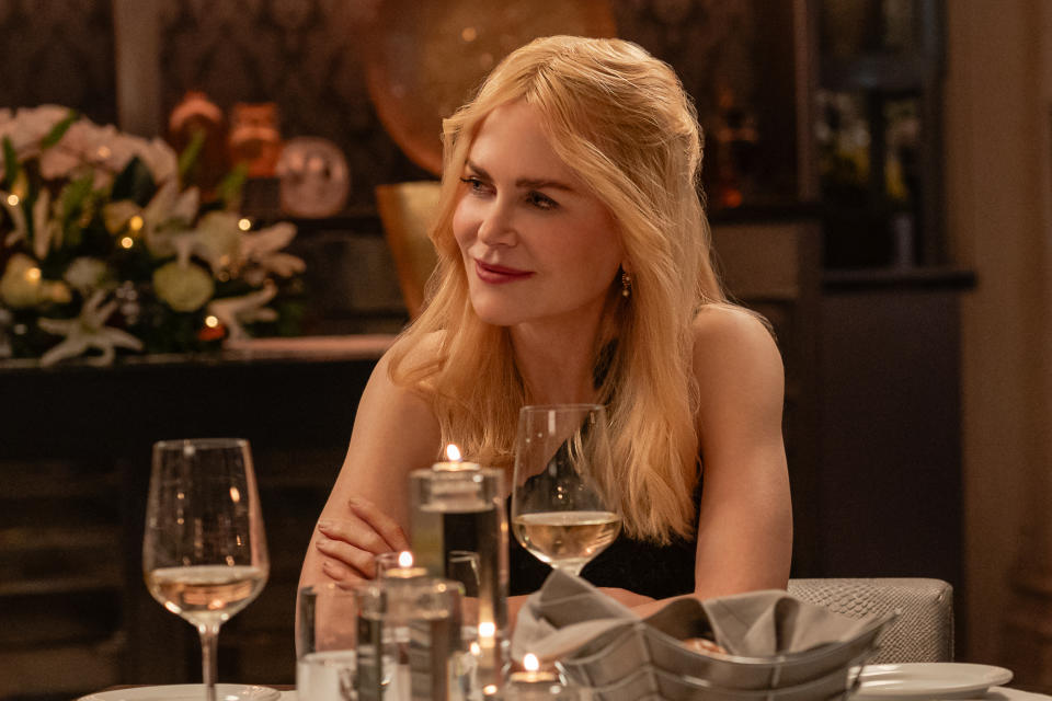 Nicole Kidman at a candlelit dinner, smiling, with wine glasses and floral arrangements in the background