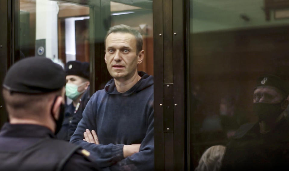 In this handout photo taken from a footage provided by Moscow City Court, Russian opposition leader Alexei Navalny stands in the cage during a hearing to a motion from the Russian prison service to convert the suspended sentence of Navalny from the 2014 criminal conviction into a real prison term in the Moscow City Court in Moscow, Russia, Tuesday, Feb. 2, 2021. A Moscow court has ordered Russian opposition leader Alexei Navalny to prison for more than 2 1/2 years for violating the terms of his probation while he was recuperating in Germany from nerve-agent poisoning. Navalny, who is the most prominent critic of President Vladimir Putin, had earlier denounced the proceedings as a vain attempt by the Kremlin to scare millions of Russians into submission. (Moscow City Court via AP)