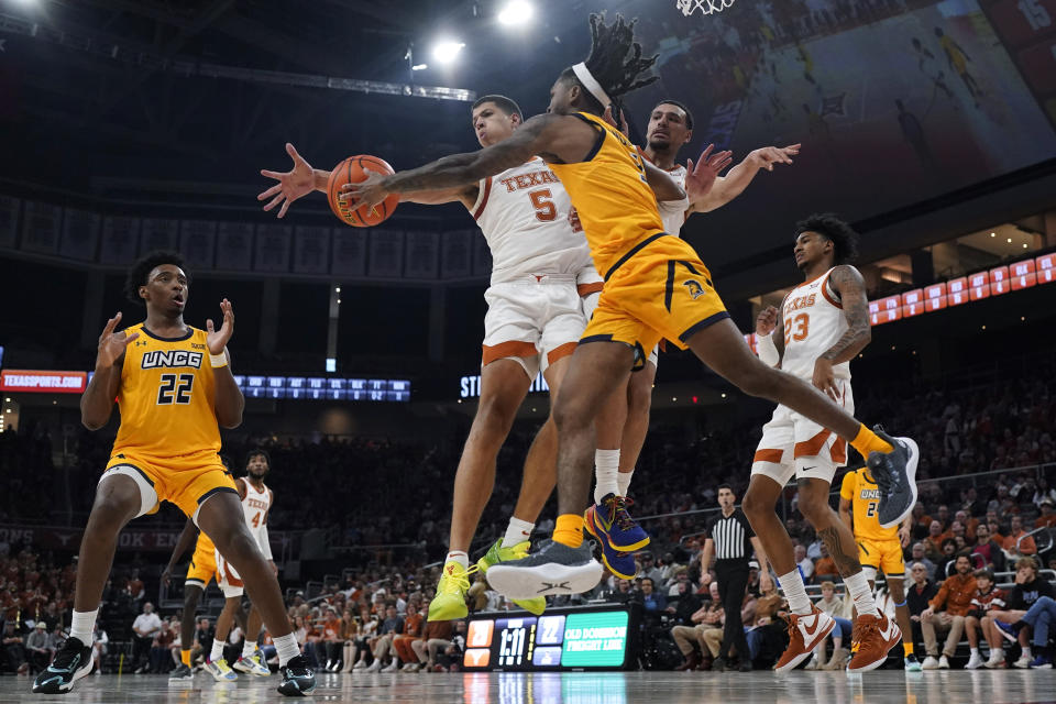 UNC Greensboro guard Kobe Langley (3) passes the ball around Texas forward Kadin Shedrick (5) during the first half of an NCAA college basketball game in Austin, Texas, Friday, Dec. 29, 2023. (AP Photo/Eric Gay)