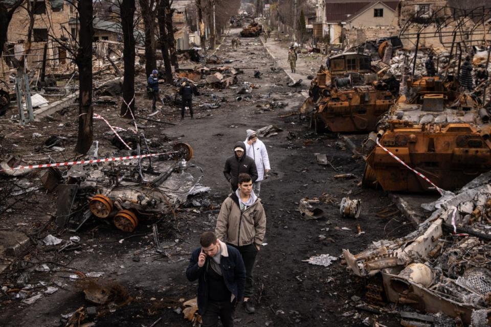 People walk through debris and destroyed Russian military vehicles on a street in Bucha, where Mykhed’s parents had been living at the start of the invasion (Getty Images)