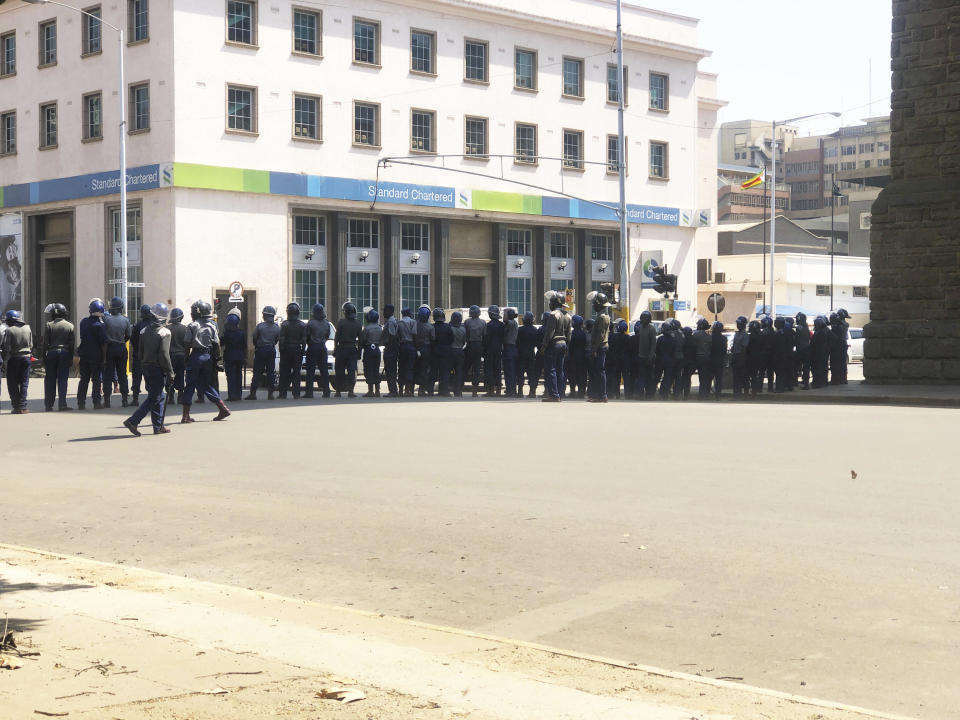 Armed Riot Police block a main road during a patrol on the streets in Harare, Thursday, Aug, 15, 2019. In a show of force to discourage anti government protests, Zimbabwe police with water cannons patrolled the capital's streets and warned residents, "you will rot in jail" if they participated in the demonstrations planned for Friday. (AP Photo/Tsvangirayi Mukwazhi)