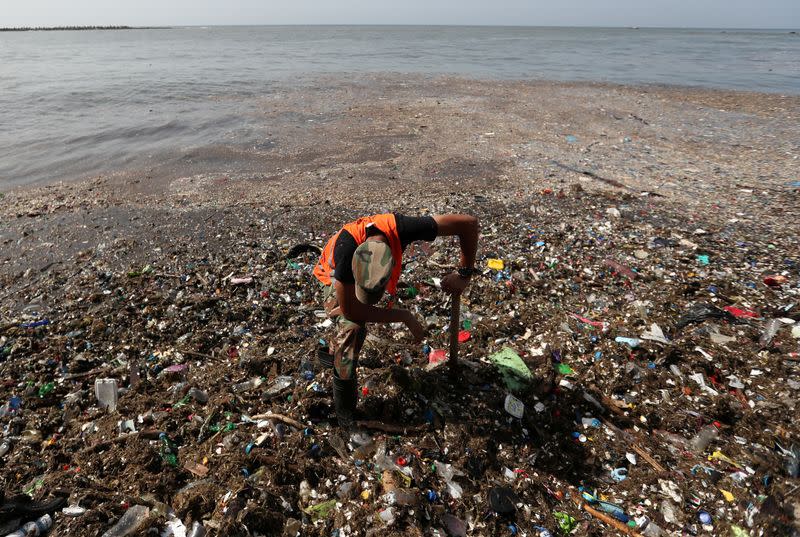 A soldier pauses while cleaning plastic and other debris on the shores of Montesinos beach, in Santo Domingo